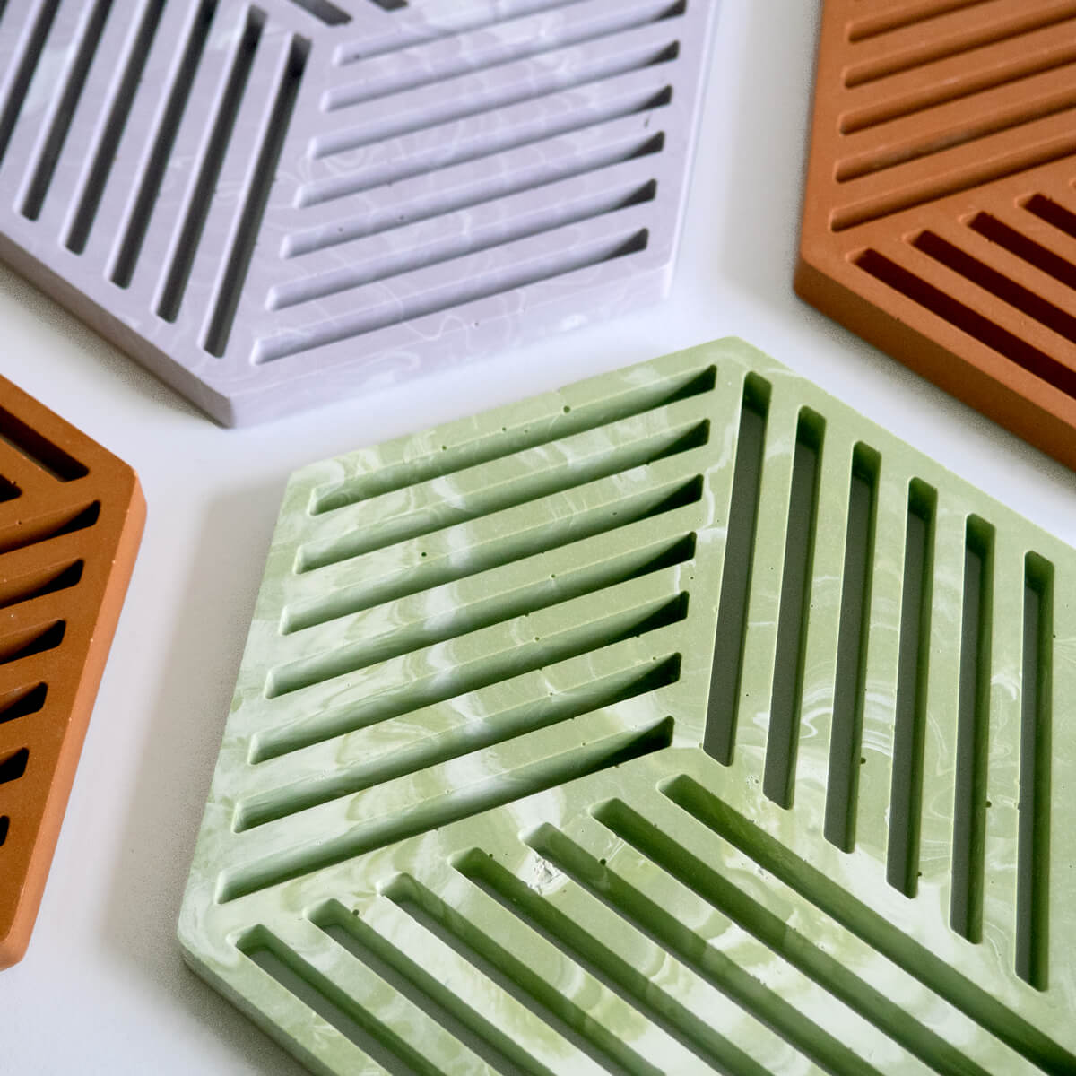 Geometric jesmonite trivets in sage green, lilac and terracotta by Klndra for Curious Makers