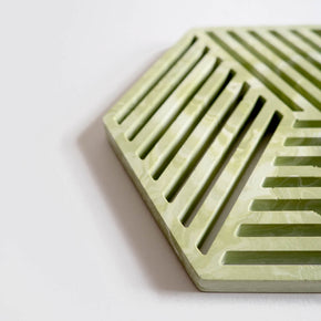 Detail of a contemporary sage green jesmonite hexagonal trivet with a subtle marbled finish by Klndra for Curious Makers