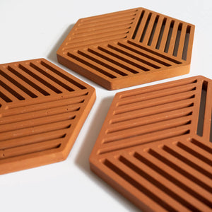Detail of three hexagonal trivets in a warm terracotta tone by Klndra for Curious Makers