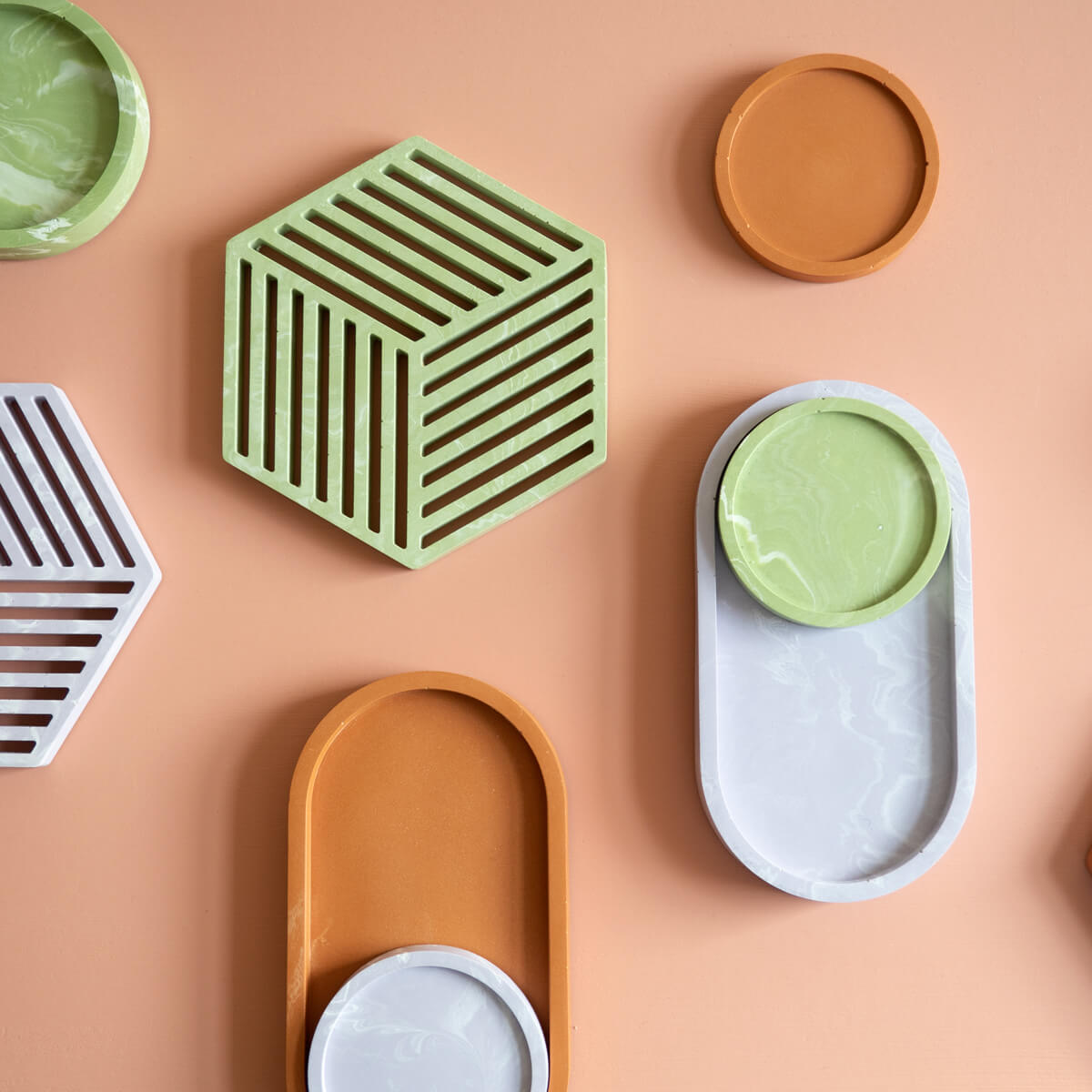 A group of handmade jesmonite coasters, trivets and trays in lilac,  sage and terracotta.