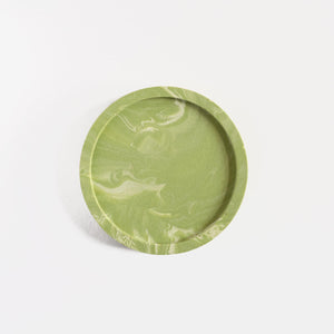 A close up of a round jesmonite coaster with sage green marble pattern handmade by Klndra for Curious Makers