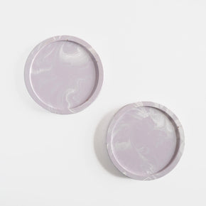 A pair of round coasters handmade using marbled jesmonite in lilac by Klndra for Curious Makers