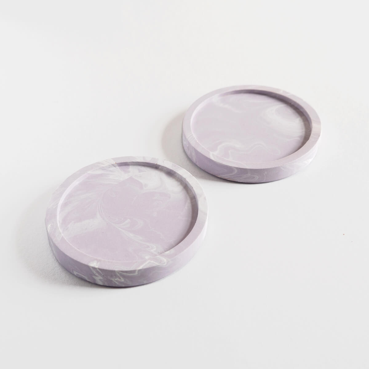 A pair of marbled lilac round coasters handmade by Klndra for Curious Makers