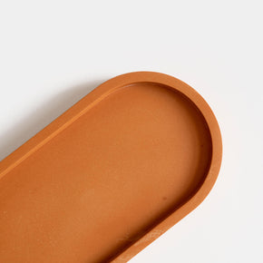 A close up of  a jesmonite oval tray in a warm terracotta hue handmade by Klndra for Curious Makers