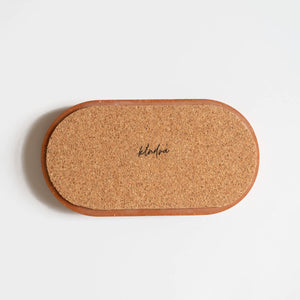 The back of  a terracotta jesmonite oval tray showing the cork base that protects your surfaces. Handmade by Klndra for Curious Makers