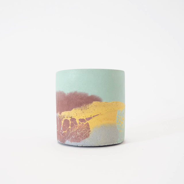 A small round concrete planter with a soft colour palette of yellow, mint, brown and lilac hues.