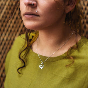 Lima Lima ecosilver eye necklace being worn by a model in a green linen top.
